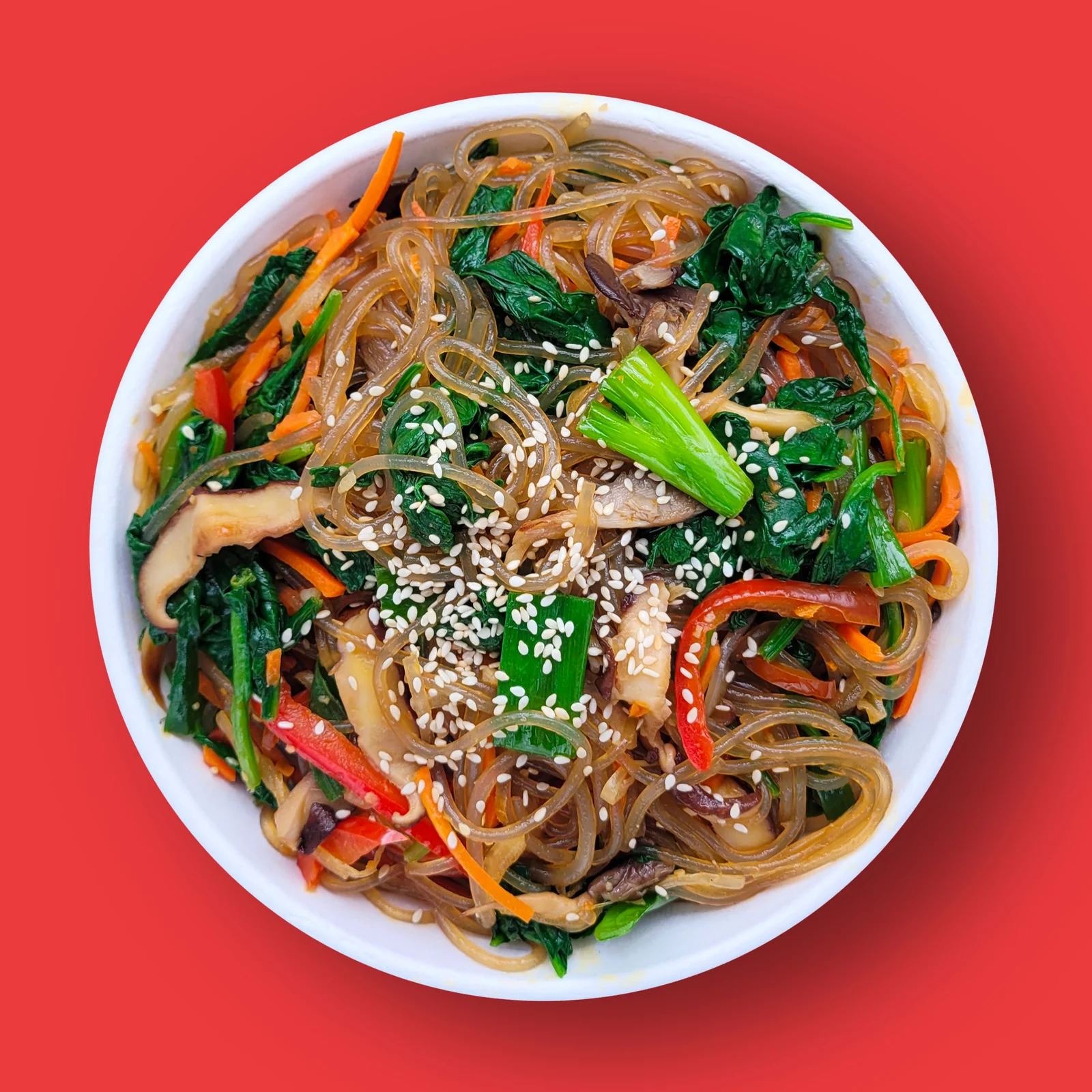 Japchae: Sweet potato starch glass noodles stir fried with vegetables and mushrooms, seasoned with soy sauce, sesame oil and chile threads