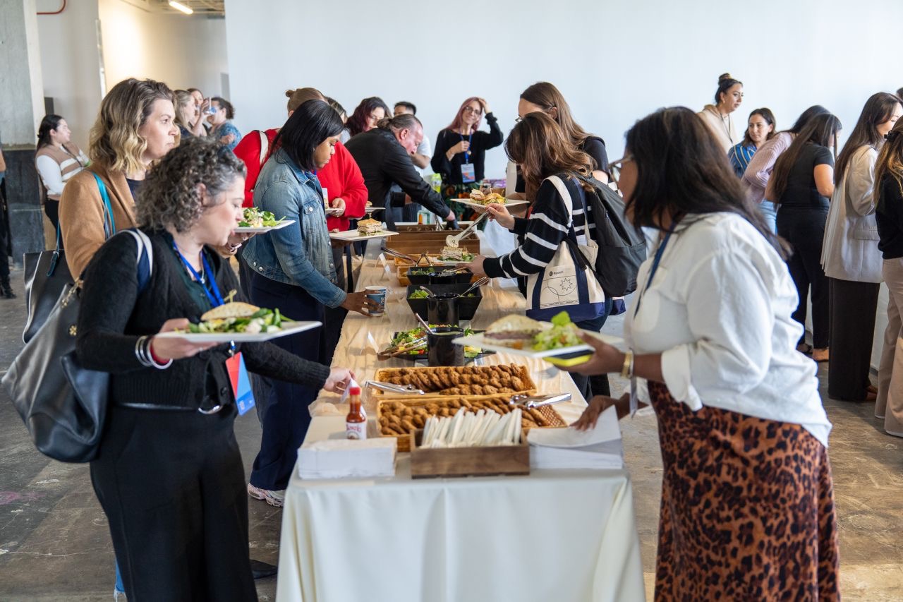 Corporate event catering San Francisco — large group of office employees serving themselves at a Superfine Kitchen buffet spread with salads, sandwiches and hot dishes